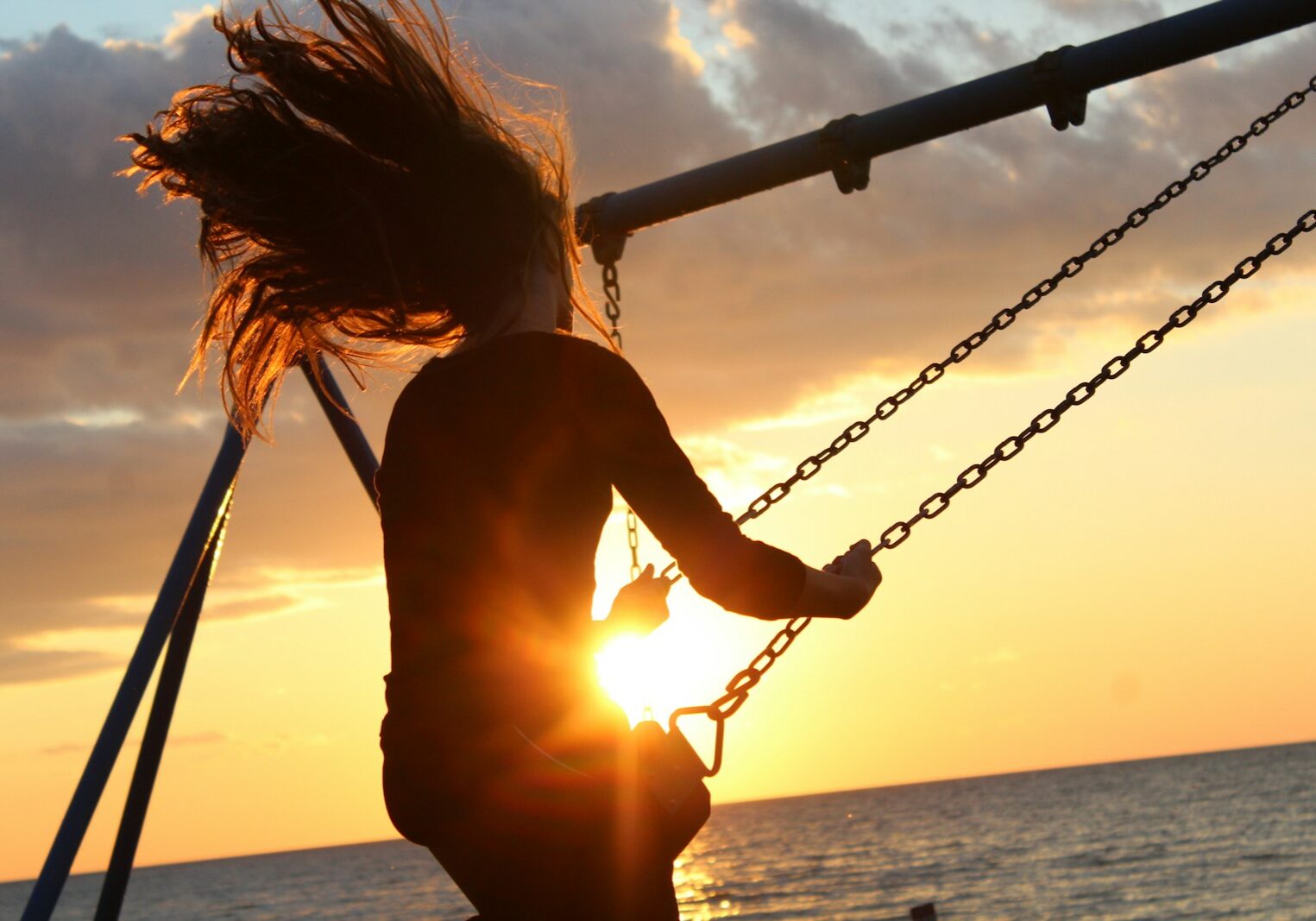 Photo by Noah Silliman woman riding on swing during sunset